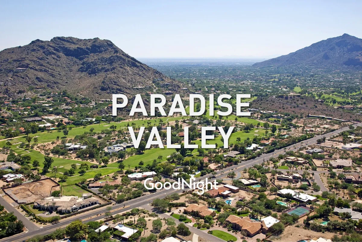 A broad view of Scottsdale's serene landscape featuring green spaces, neighborhood houses, winding roadways, and distant mountains. The atmosphere is calm and inviting, suggesting places to walk and explore with pets.