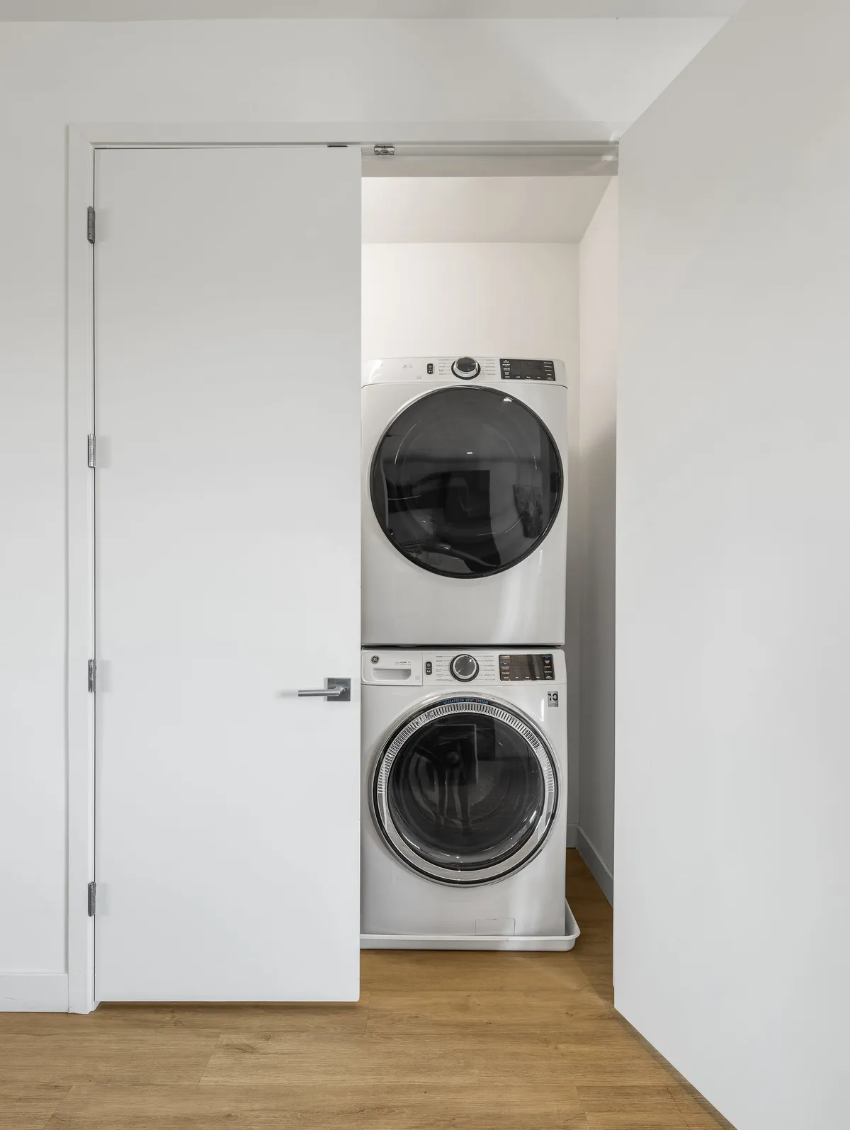 A compact laundry nook with stacked washer and dryer units behind clean white doors. The area is organized and efficient, providing convenience for extended stays or families.