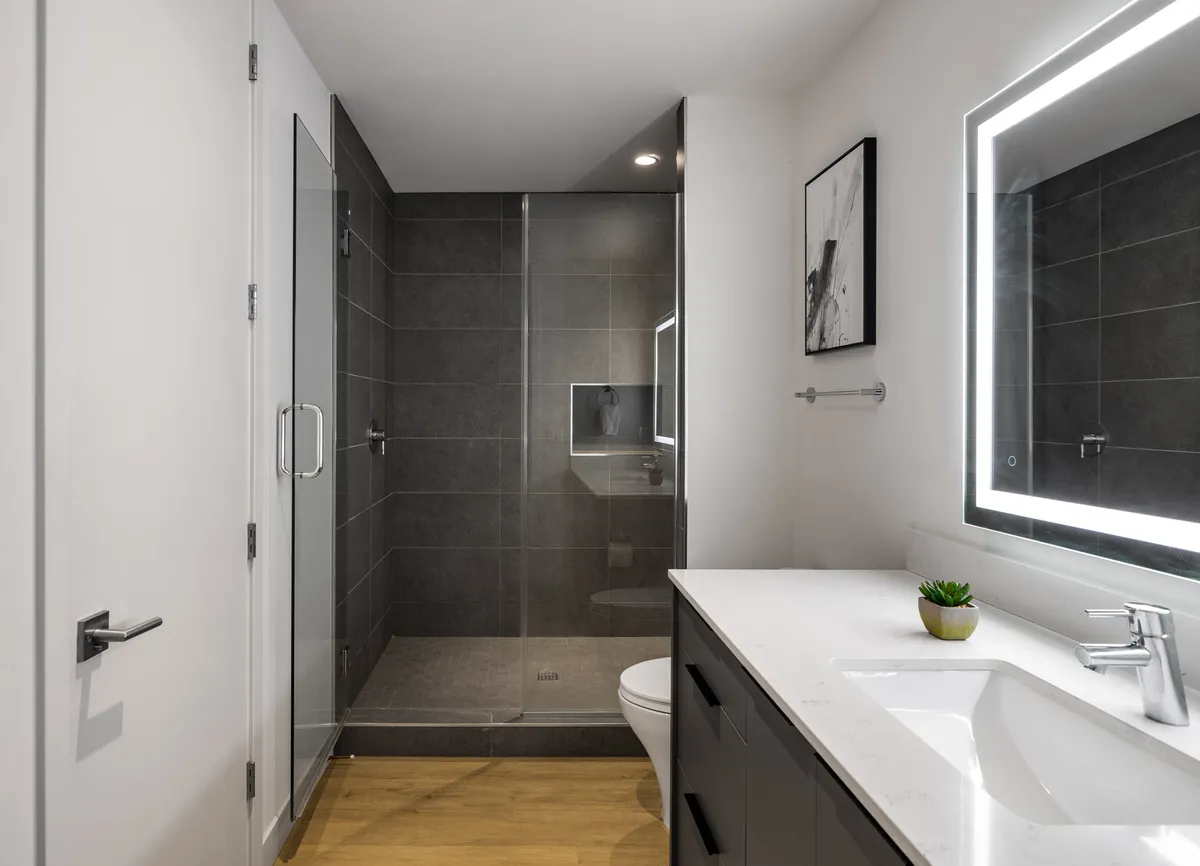 A modern bathroom featuring a walk-in shower, sleek vanity with a backlit mirror, and contemporary artwork. The space feels inviting and spa-like, ideal for self-care and rejuvenation.