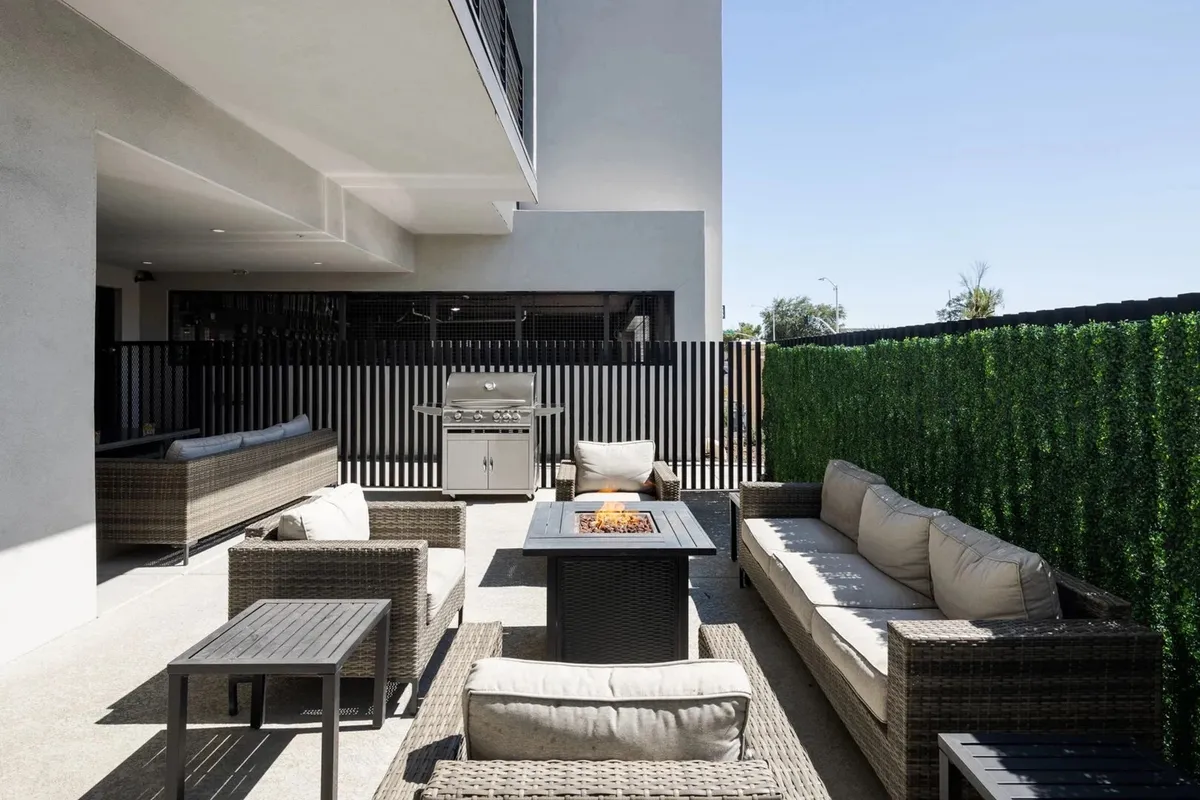 A vibrant outdoor space featuring a cozy fire pit surrounded by seating, a BBQ grill, and ample space for group activities. The backdrop suggests relaxed evenings and lively gatherings under open skies.