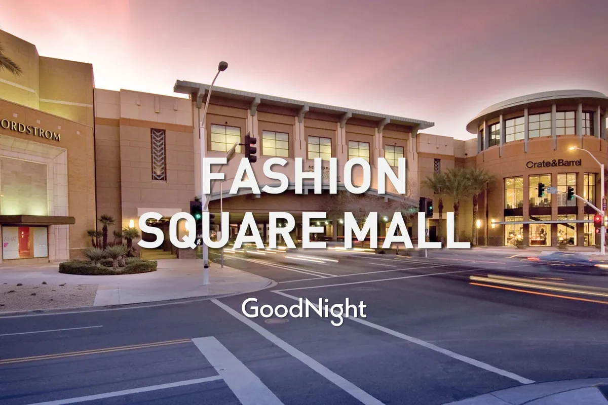 The bustling entrance of a high-end shopping complex with the Nordstrom and Crate & Barrel storefronts, set among palm trees and city life. The scene captures a vibrant hub for upscale shopping and dining, evocative of Scottsdale's lively Fashion Square district.